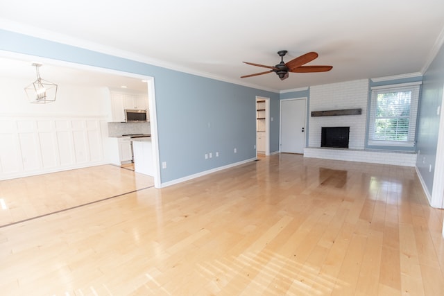 unfurnished living room featuring light hardwood / wood-style flooring, ceiling fan, a fireplace, and crown molding