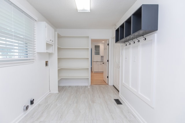 mudroom with a textured ceiling and light hardwood / wood-style floors