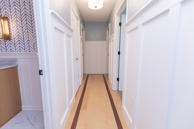 hall featuring a textured ceiling and light hardwood / wood-style flooring