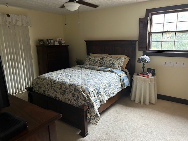 bedroom with a textured ceiling, ceiling fan, and light carpet