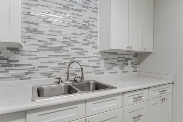 kitchen with decorative backsplash, sink, and white cabinets