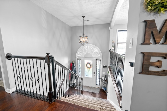 entrance foyer with a chandelier, a textured ceiling, and dark wood-type flooring