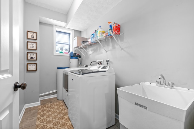 washroom with sink, washer and dryer, and a textured ceiling