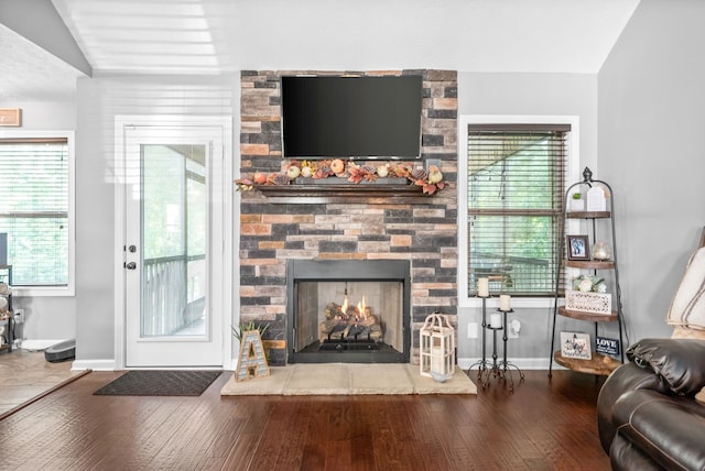 living room featuring wood-type flooring, lofted ceiling, and a fireplace