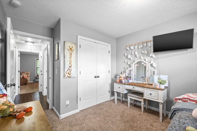 bedroom featuring a textured ceiling, dark colored carpet, and a closet