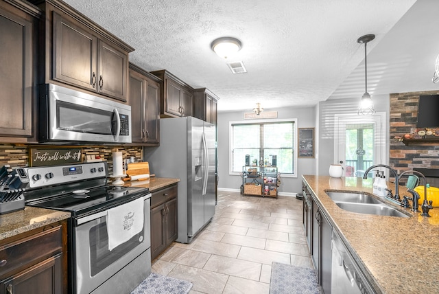 kitchen with pendant lighting, a textured ceiling, appliances with stainless steel finishes, and sink