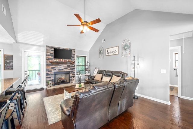 living room featuring ceiling fan, a stone fireplace, dark wood-type flooring, and high vaulted ceiling