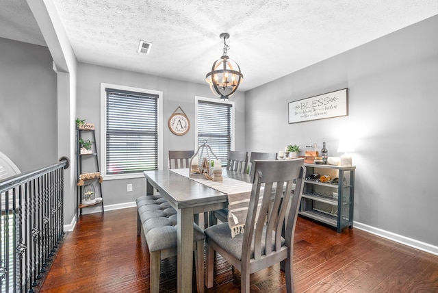 dining room featuring a textured ceiling, dark wood-type flooring, and a notable chandelier