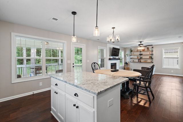 kitchen with light stone counters, white cabinets, dark hardwood / wood-style floors, and plenty of natural light