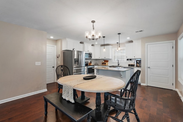 dining space featuring a notable chandelier, sink, and dark wood-type flooring