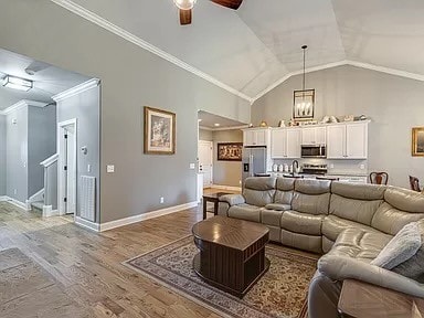 living room featuring light hardwood / wood-style flooring, vaulted ceiling, ceiling fan, and crown molding