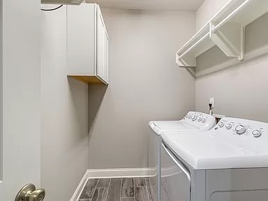 clothes washing area featuring separate washer and dryer, hardwood / wood-style floors, and cabinets