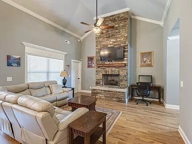 living room with light hardwood / wood-style flooring, ornamental molding, ceiling fan, and a fireplace