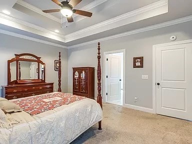 bedroom with ornamental molding, a tray ceiling, light carpet, and ceiling fan