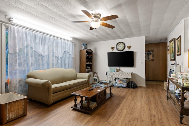 living room featuring wooden walls, hardwood / wood-style floors, and ceiling fan