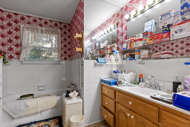 bathroom with vanity, a bathtub, a textured ceiling, tile walls, and crown molding