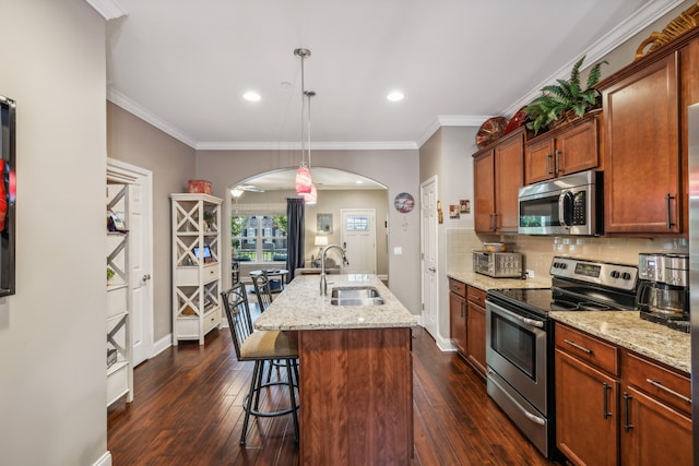 kitchen featuring dark wood-type flooring, sink, a center island with sink, appliances with stainless steel finishes, and decorative light fixtures