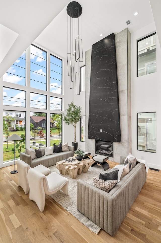 living room with a high ceiling, light hardwood / wood-style flooring, and a notable chandelier