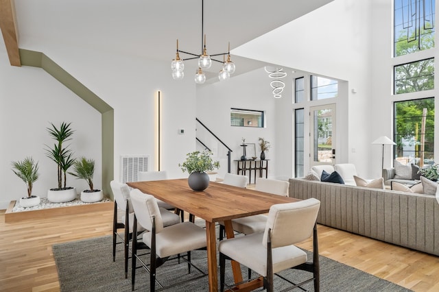 dining area with a notable chandelier, a high ceiling, and hardwood / wood-style flooring