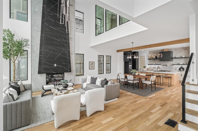 living room featuring a notable chandelier, hardwood / wood-style flooring, plenty of natural light, and a high ceiling