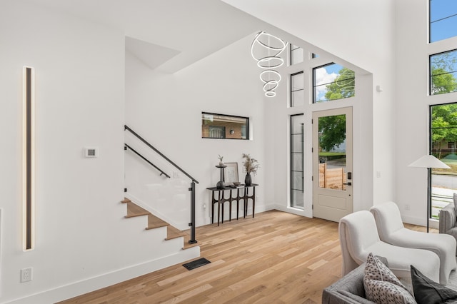 entrance foyer featuring a towering ceiling, light hardwood / wood-style floors, and plenty of natural light