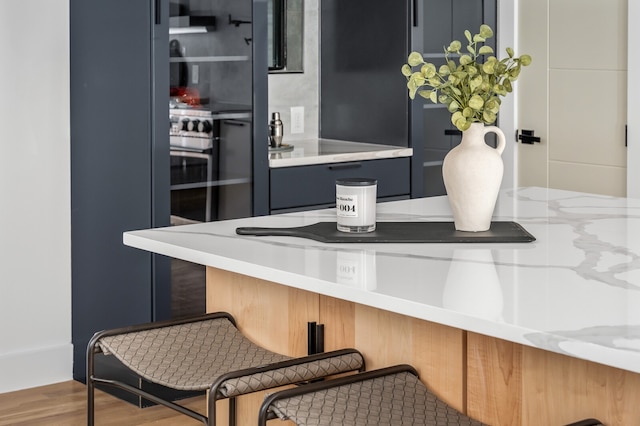 kitchen with light stone countertops, wood-type flooring, and ventilation hood