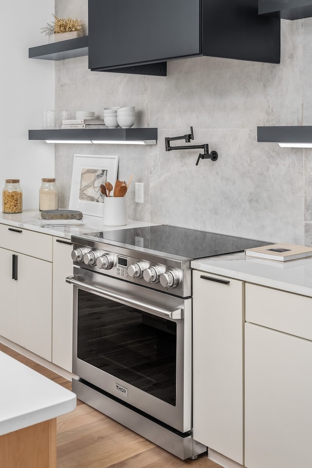 kitchen featuring high end stove, light hardwood / wood-style floors, and white cabinets