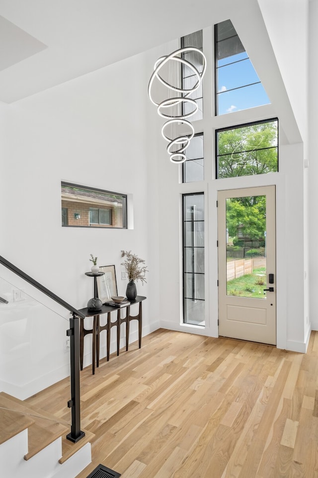 foyer with an inviting chandelier, light hardwood / wood-style floors, and a high ceiling