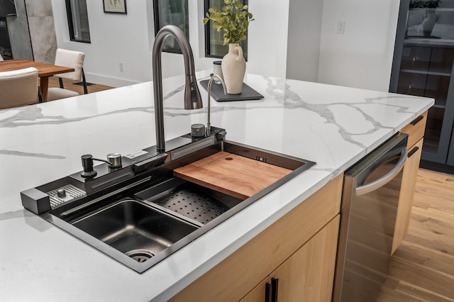 kitchen with light stone countertops, dishwasher, hardwood / wood-style floors, and sink