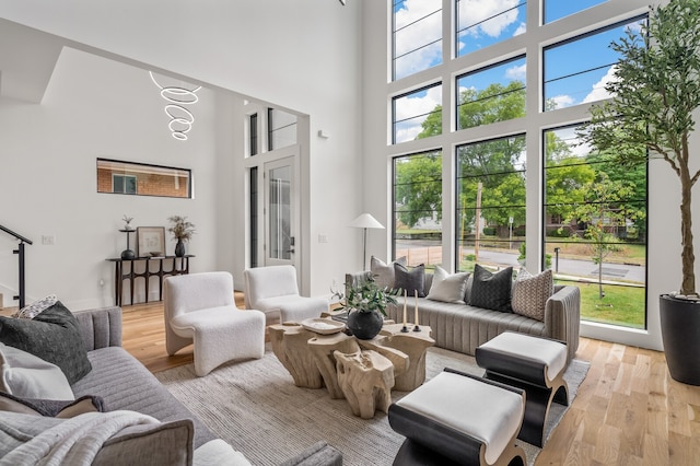 living room featuring a towering ceiling, light hardwood / wood-style floors, and a wealth of natural light