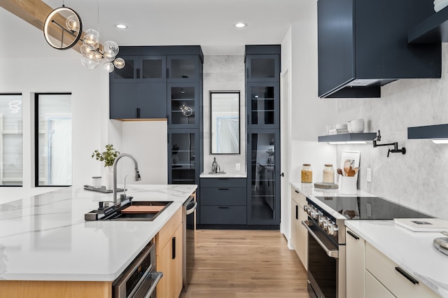 kitchen with light stone countertops, stainless steel appliances, hanging light fixtures, and blue cabinetry