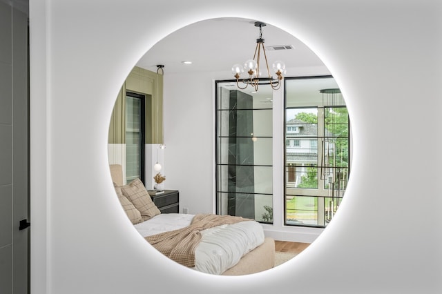 living area with an inviting chandelier, hardwood / wood-style floors, and a healthy amount of sunlight