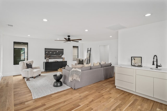 living room featuring light wood-type flooring, ceiling fan, and sink