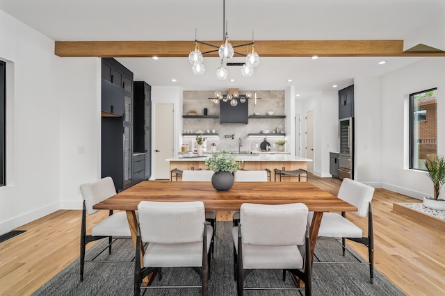 dining space featuring beam ceiling, sink, a chandelier, and hardwood / wood-style flooring