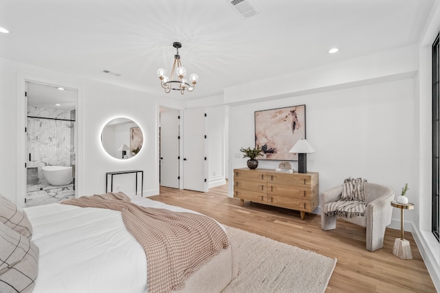 bedroom with a notable chandelier, ensuite bath, and light hardwood / wood-style floors