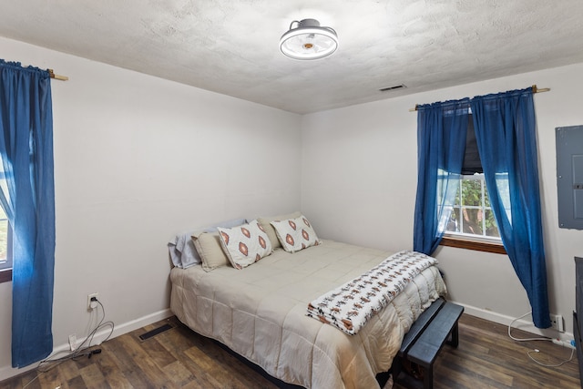 bedroom with a textured ceiling, dark hardwood / wood-style floors, and electric panel