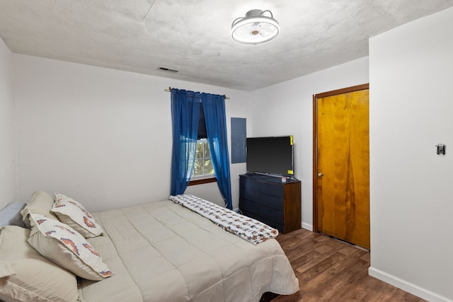 bedroom featuring electric panel, a textured ceiling, and dark hardwood / wood-style floors