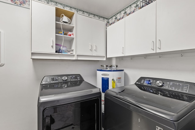 clothes washing area featuring electric water heater, separate washer and dryer, and cabinets