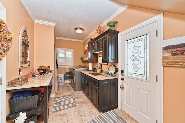 kitchen with dark brown cabinets, ornamental molding, sink, and washer and dryer