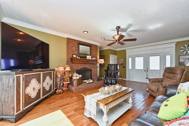 living room with ornamental molding, a brick fireplace, light hardwood / wood-style floors, and ceiling fan