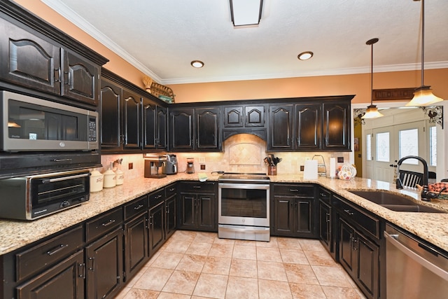 kitchen with pendant lighting, ornamental molding, sink, stainless steel appliances, and light stone countertops