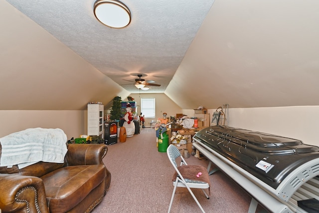 interior space with a textured ceiling, carpet flooring, vaulted ceiling, and ceiling fan