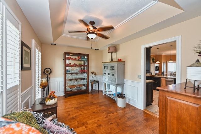 living room featuring ceiling fan, a tray ceiling, and dark wood-type flooring