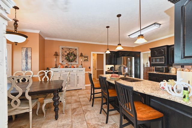 kitchen featuring light stone counters, stainless steel appliances, crown molding, a kitchen bar, and decorative light fixtures