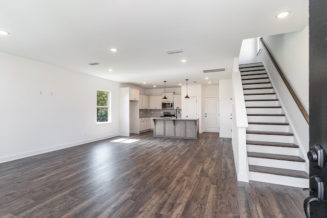 unfurnished living room featuring dark hardwood / wood-style floors and sink