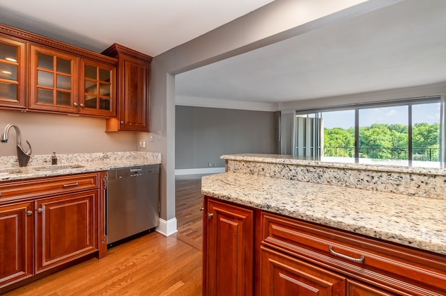 kitchen with light stone counters, light hardwood / wood-style floors, sink, and stainless steel dishwasher