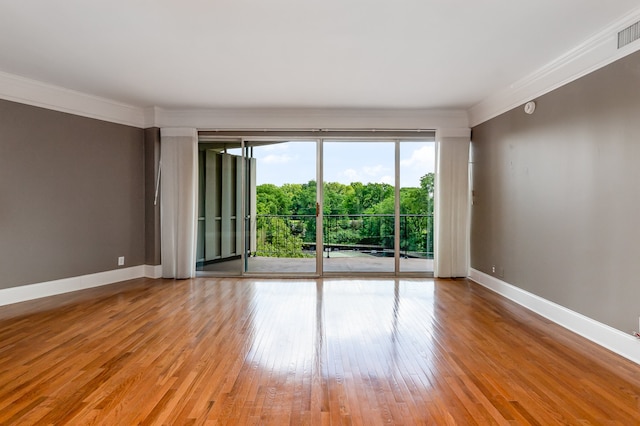 empty room featuring light wood-type flooring and crown molding