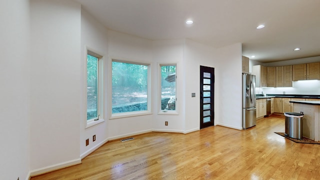 kitchen featuring light wood-type flooring, plenty of natural light, and stainless steel fridge