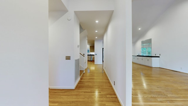 hall with a towering ceiling and light wood-type flooring