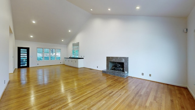 unfurnished living room featuring high vaulted ceiling and light wood-type flooring